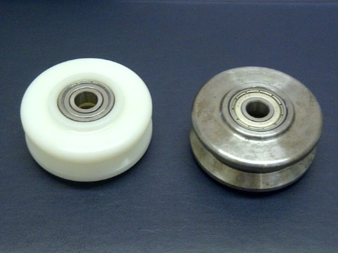 Plastic guide roller alongside its steel equivalent